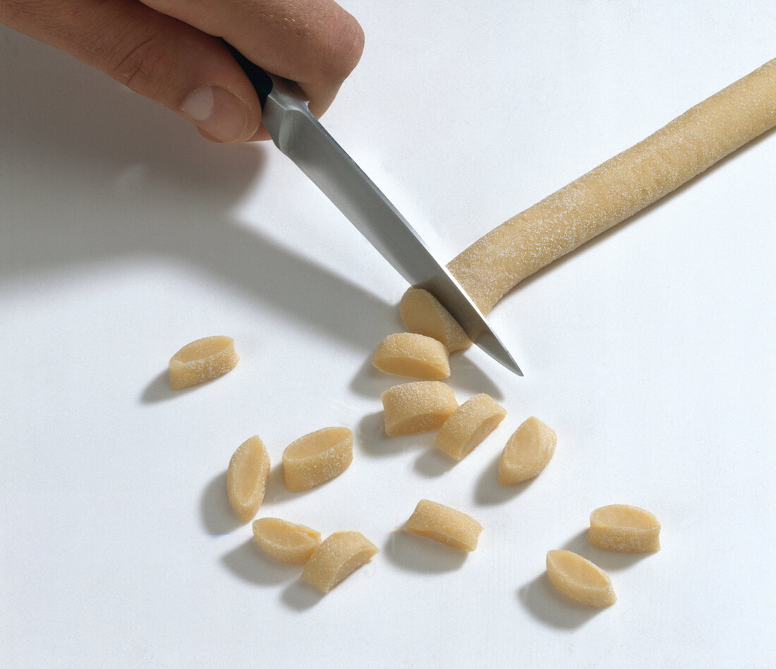 Hand cutting dough with knife for preparing orecchiette pasta, step 2