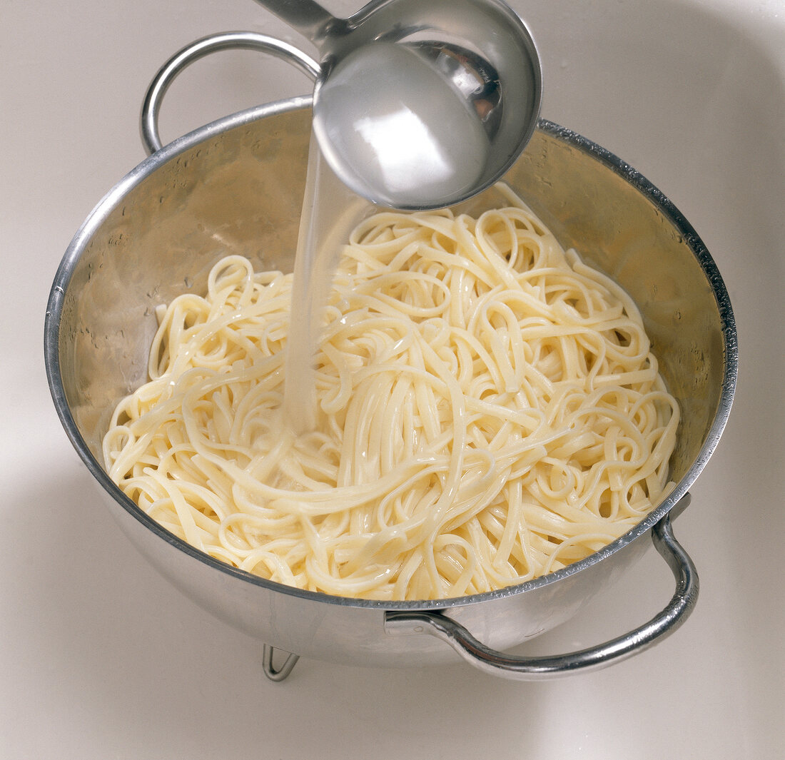 Noodles being doused in colander with hot cooking water