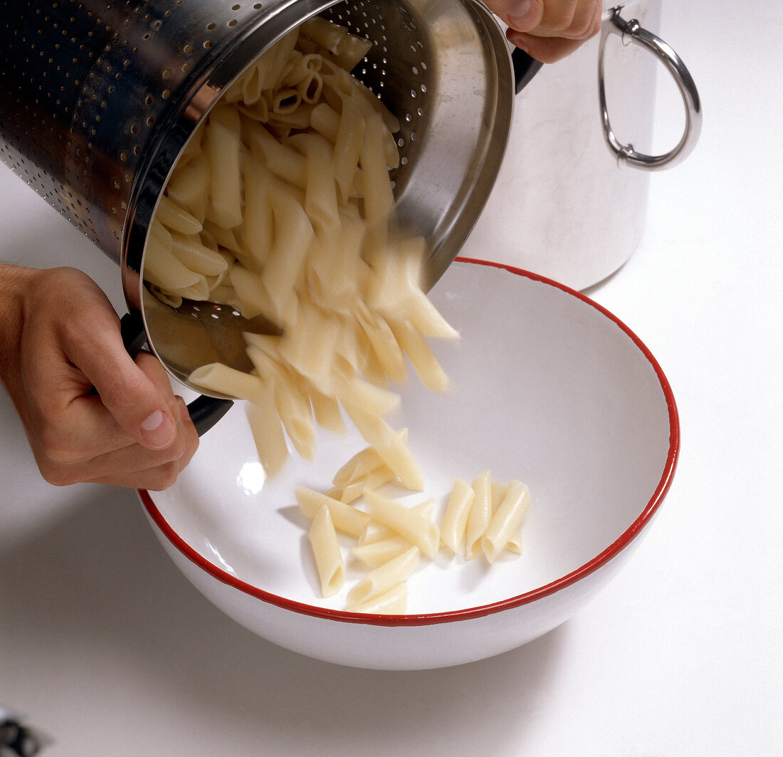 Boiled noodles being put in preheated bowl for preparing pasta, step 4