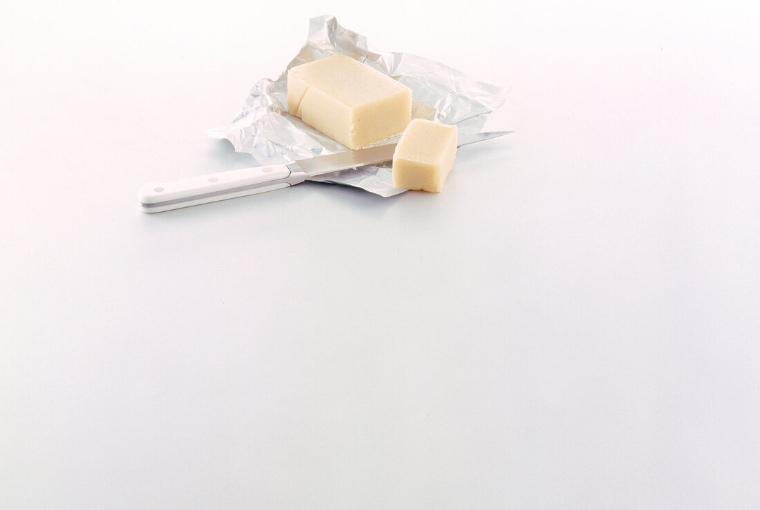 Piece of butter with knife on silver foil