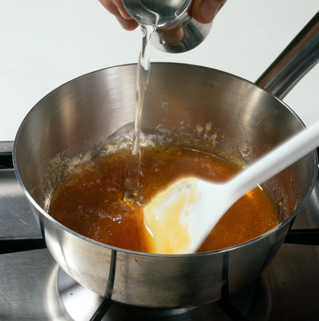 Water being poured in caramelized sugar in sauce pan