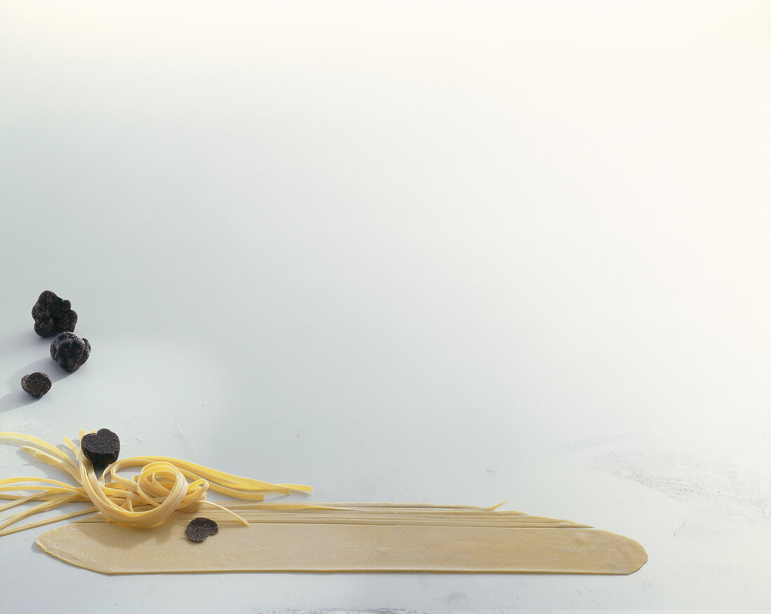 Fresh truffles and raw homemade noodles on white background, copy space