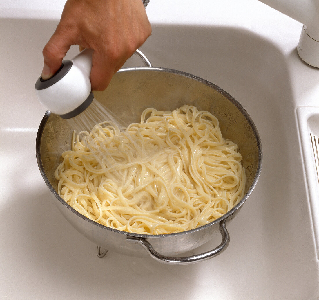 Noodles in casserole being rinsed with cold water