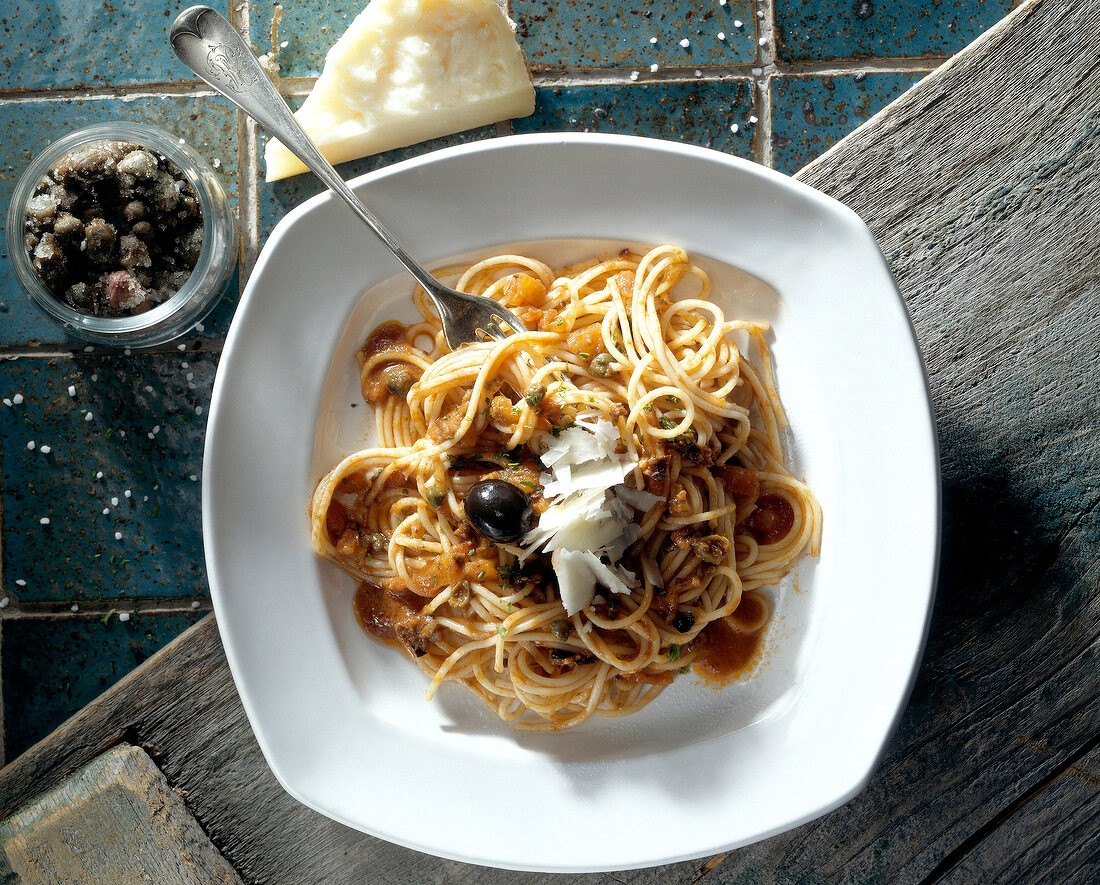 Spaghetti with capers sauce and pecorino flakes on plate