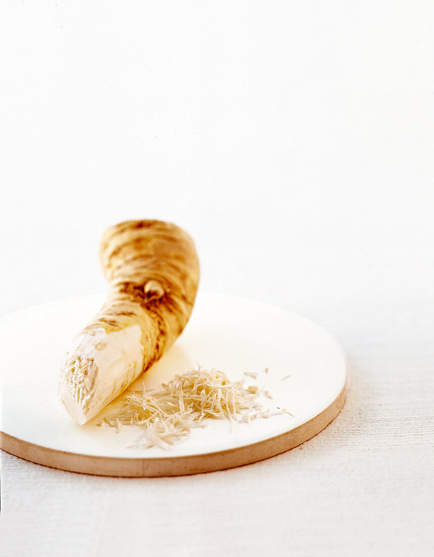 Grated horseradish on round chopping board