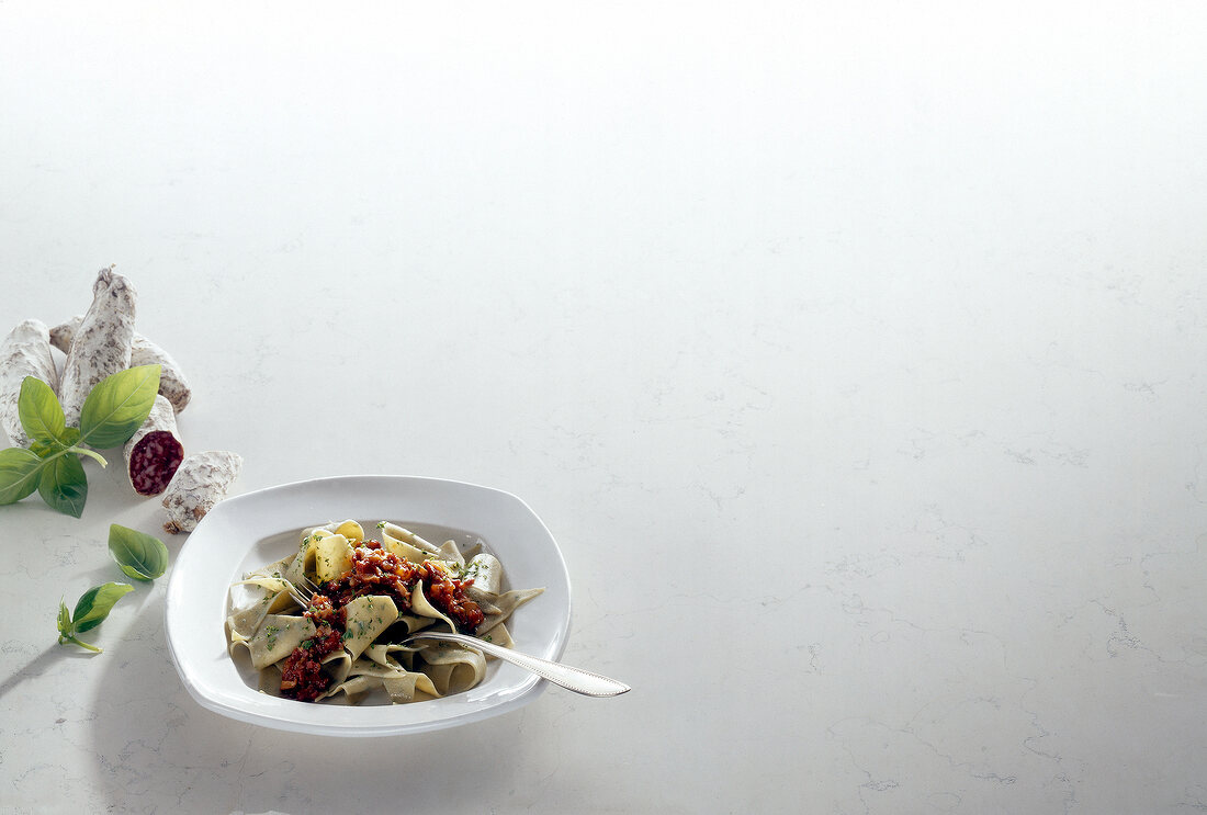 Basil pasta with salsa di salsiccia on plate, copy space