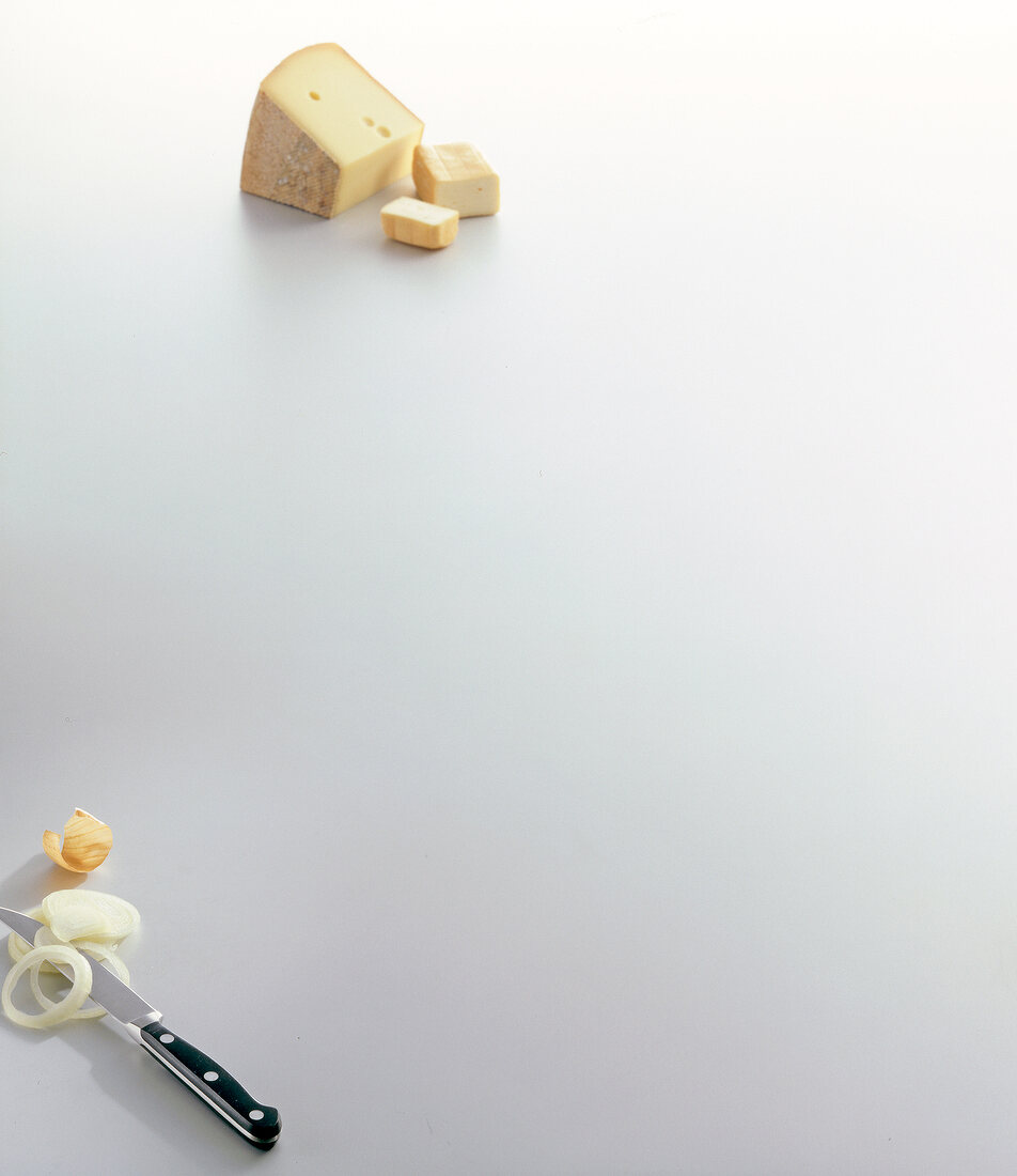 Cheese with onion rings and knife on white background, copy space