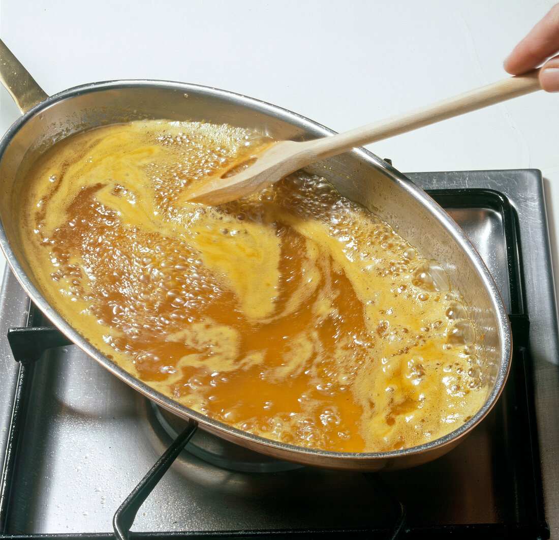 Hand stirring lime and orange juice with hot butter in pan