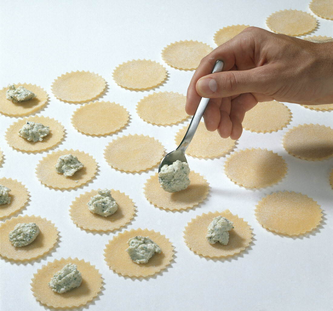 Stuffing being put on round pasta dough while preparing tortelloni, step 2