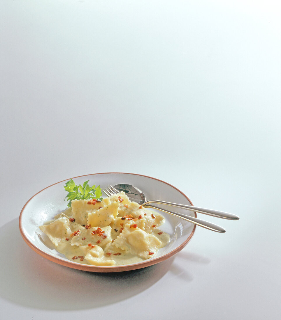 Ravioli pasta on plate with spoon and fork