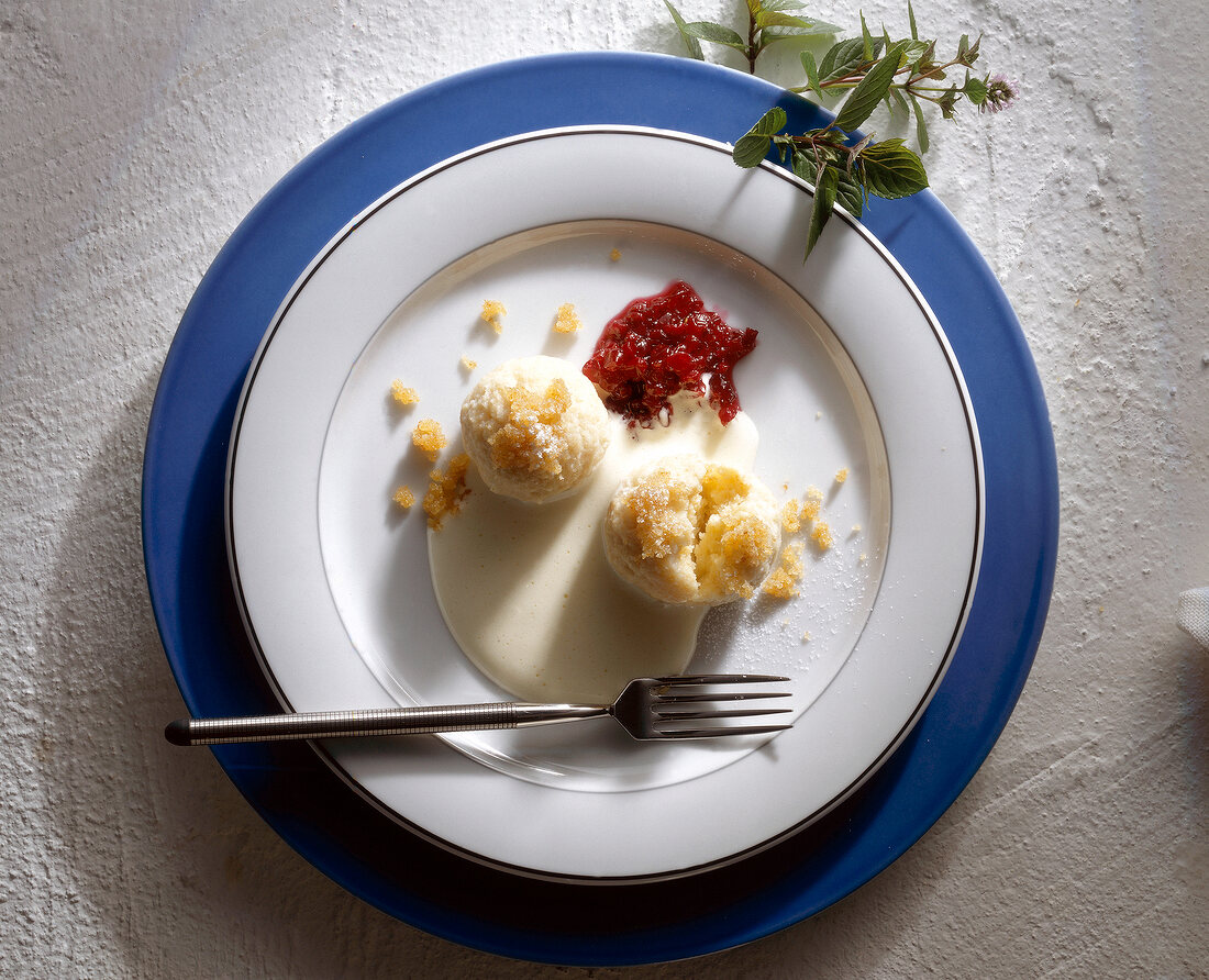 Curd cheese dumplings with cranberries and sabayon on plate