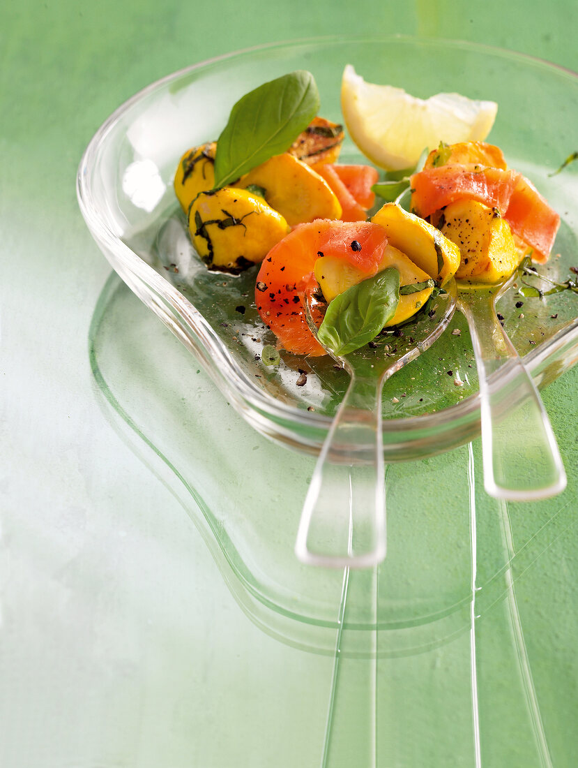 Pickled patissons with lemon and basil on glass plate