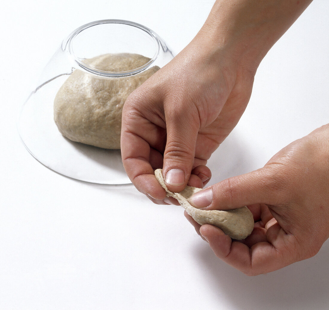 Noodles dough being pressed with thumps while preparing pasta, step 1