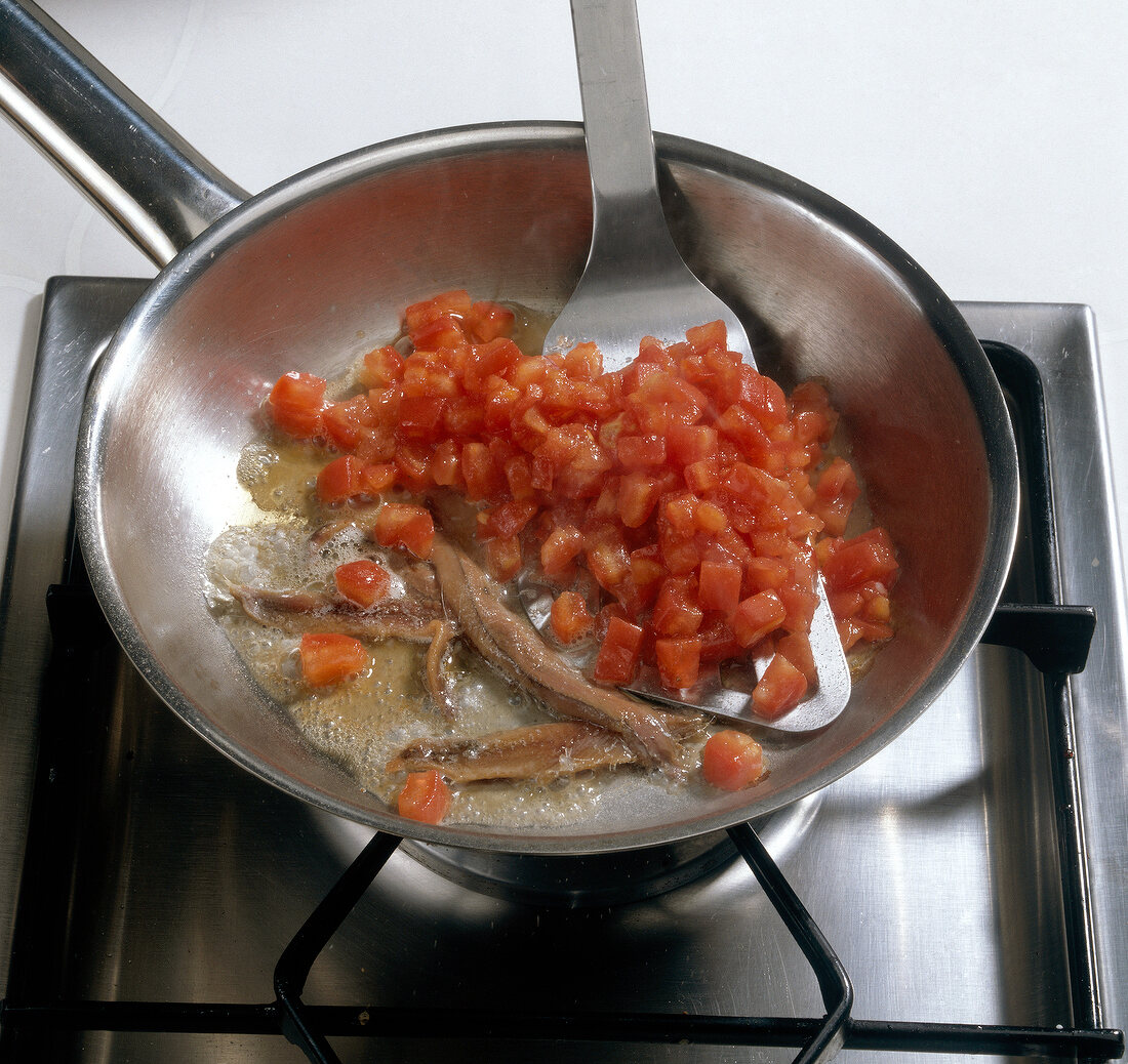 Teigwaren. Tomatensauce wird zubereitet: Sardellenfilets anbraten