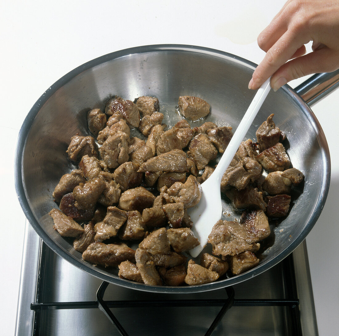 Meat cubes being fried in pan, step 1