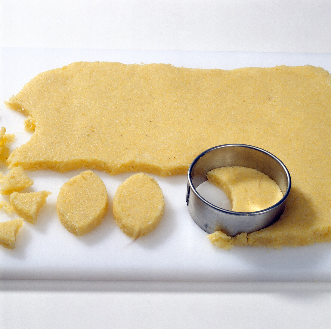 Dough being cut with round cookie cutter on cutting board