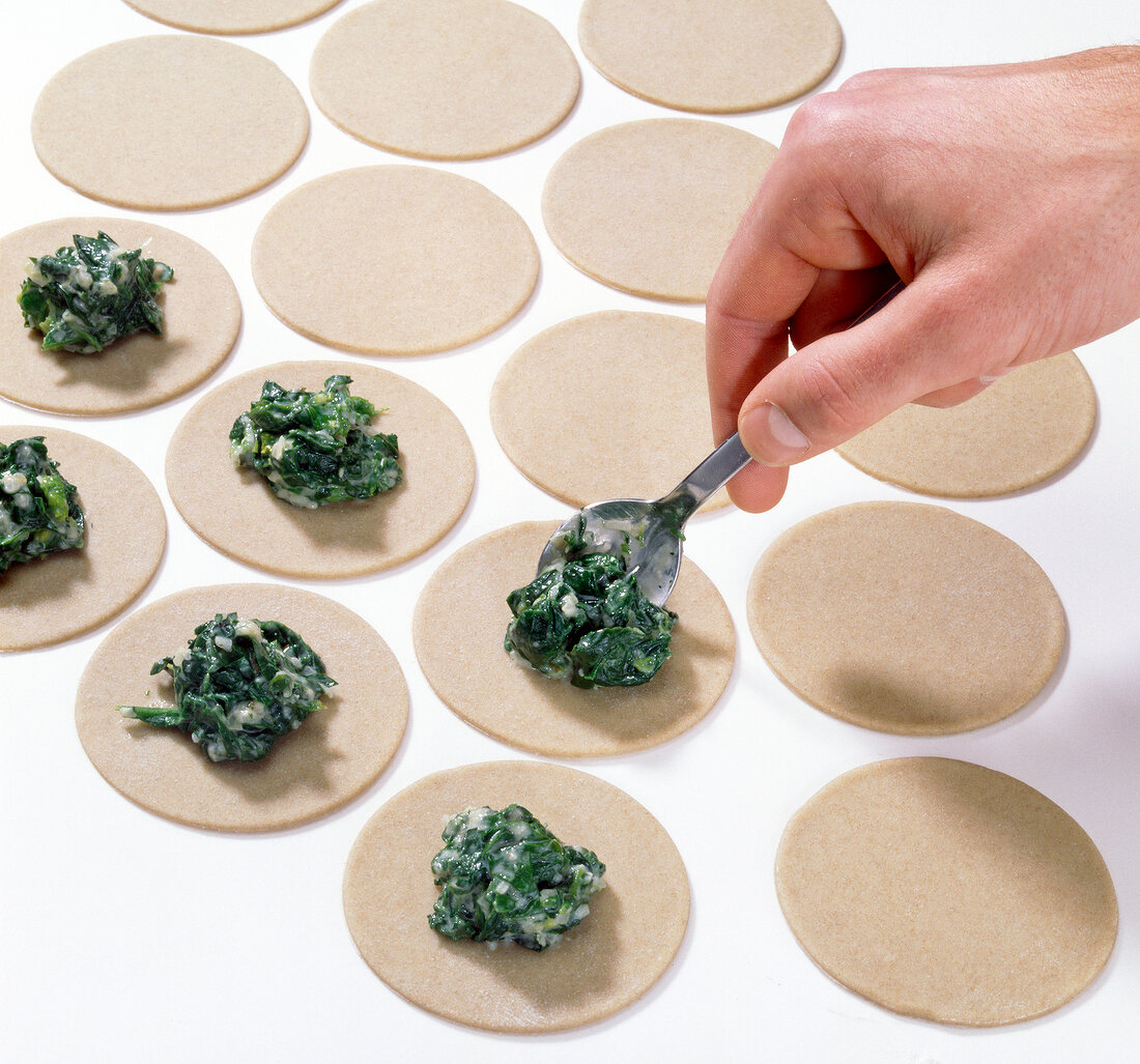 Filling being put on dough discs with spoon