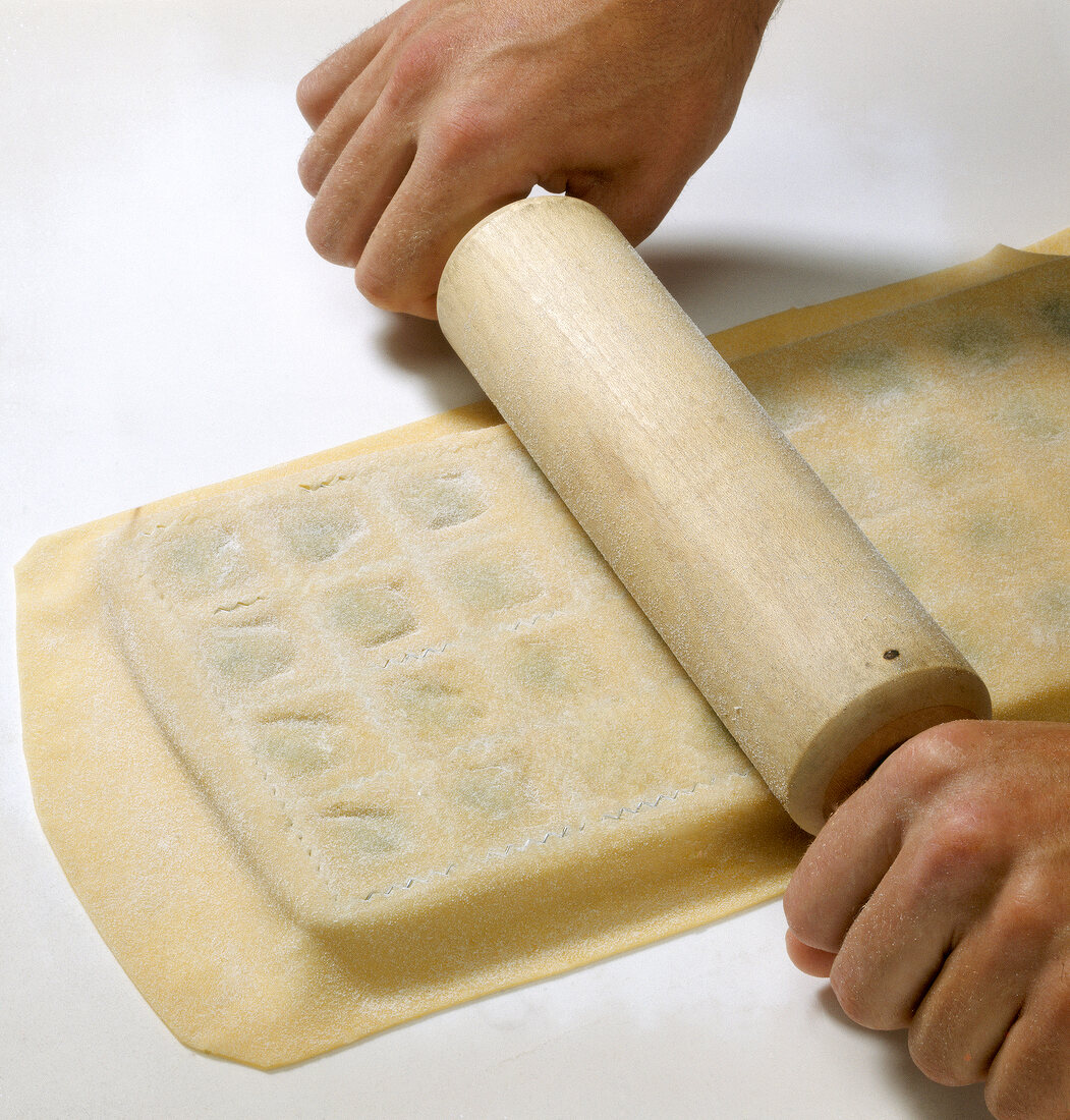 Dough being rolled over pasta dough sheet with rolling pin