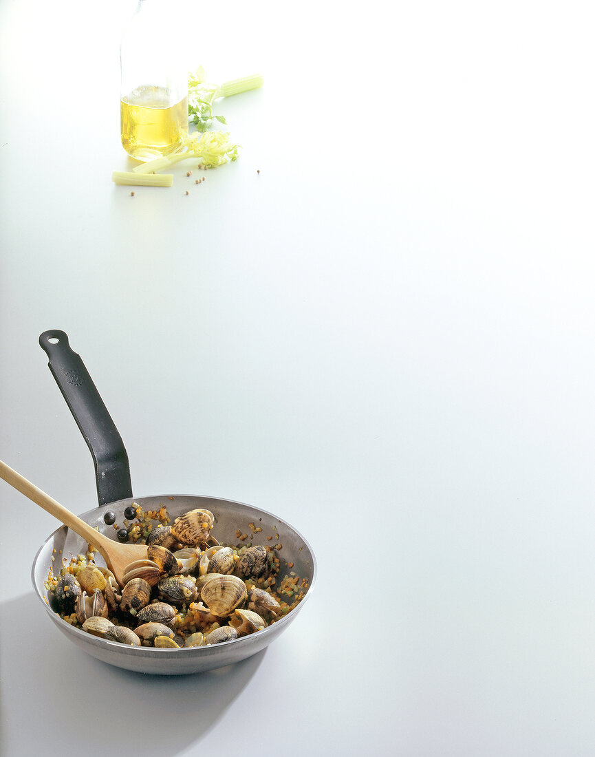 Mussels in pan, celery and bottle of oil on white background, copy space