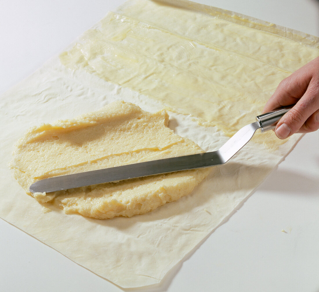 Semolina dough being spread on baking paper greased with butter