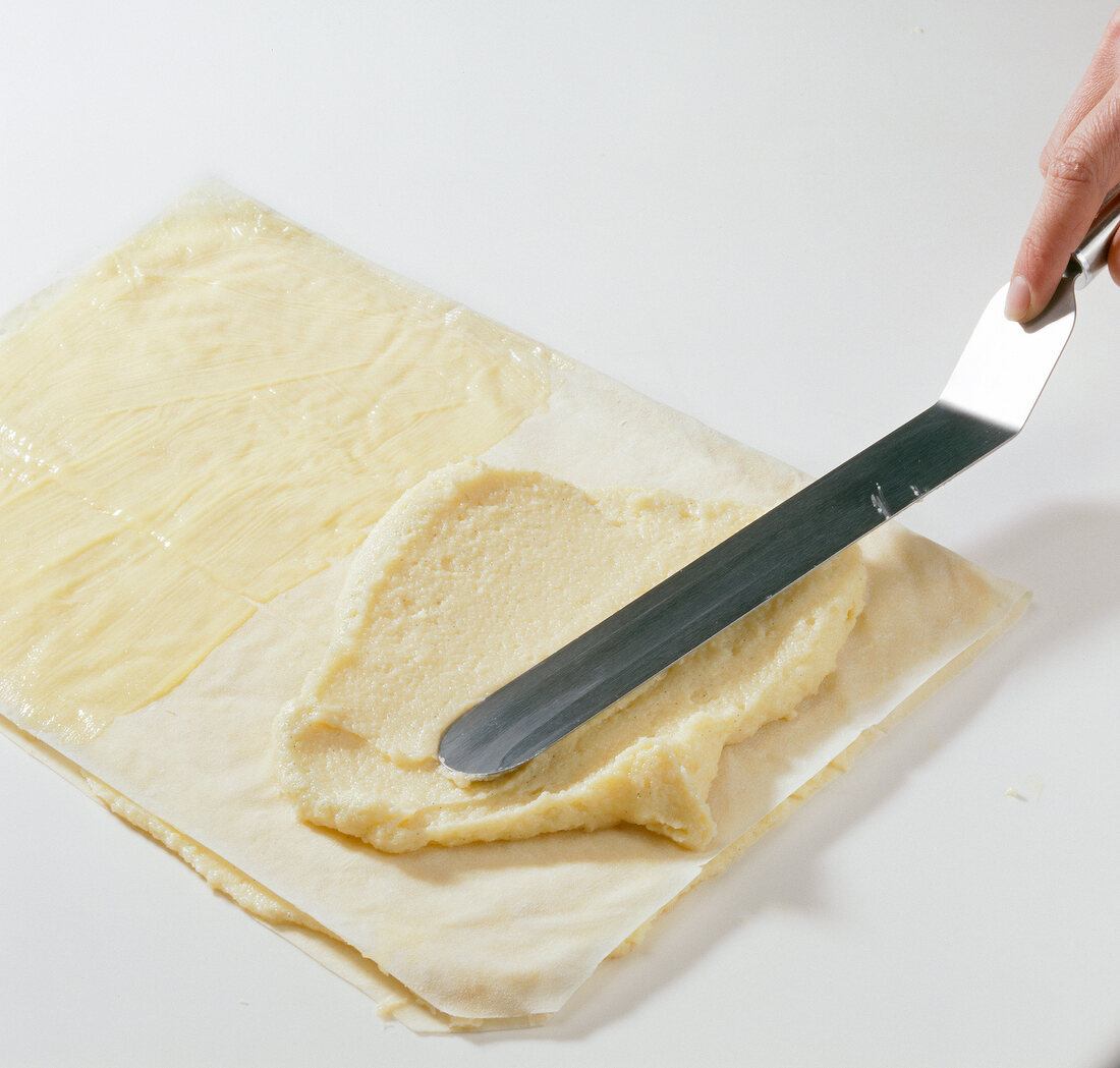 Half folded baking paper greased with butter and porridge being spread on it