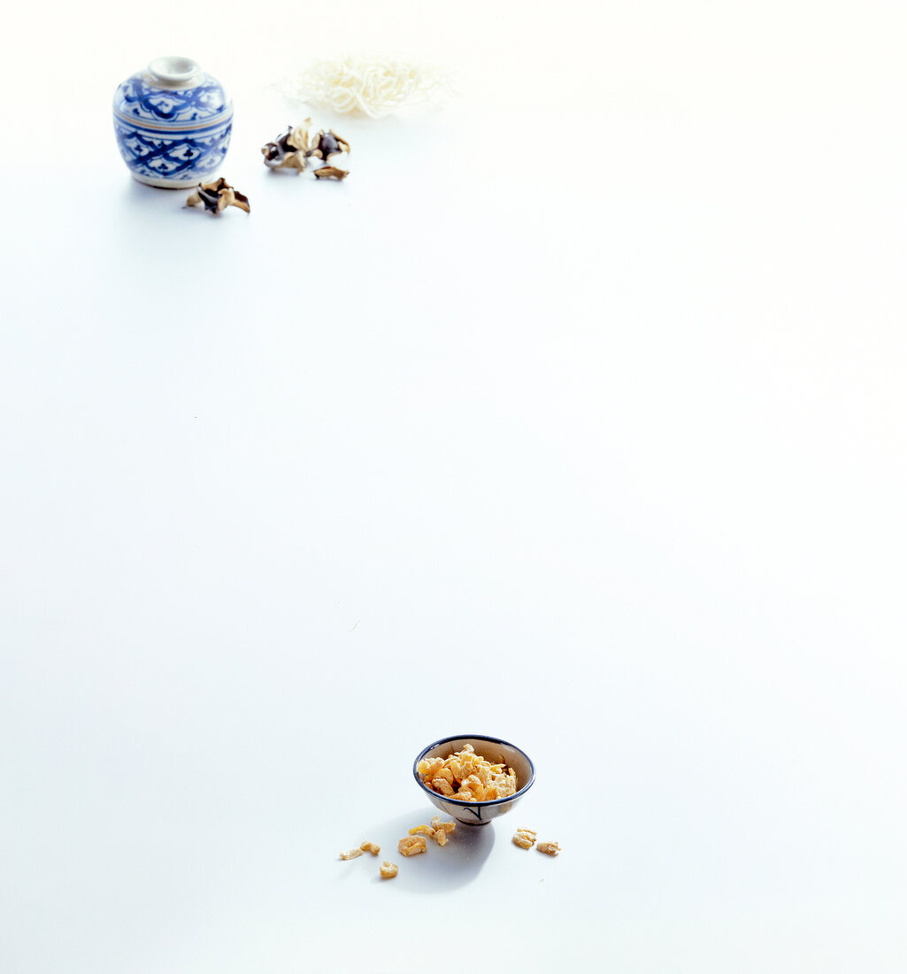 Dried mushrooms and pieces of shrimp in small bowl on white background, copy space