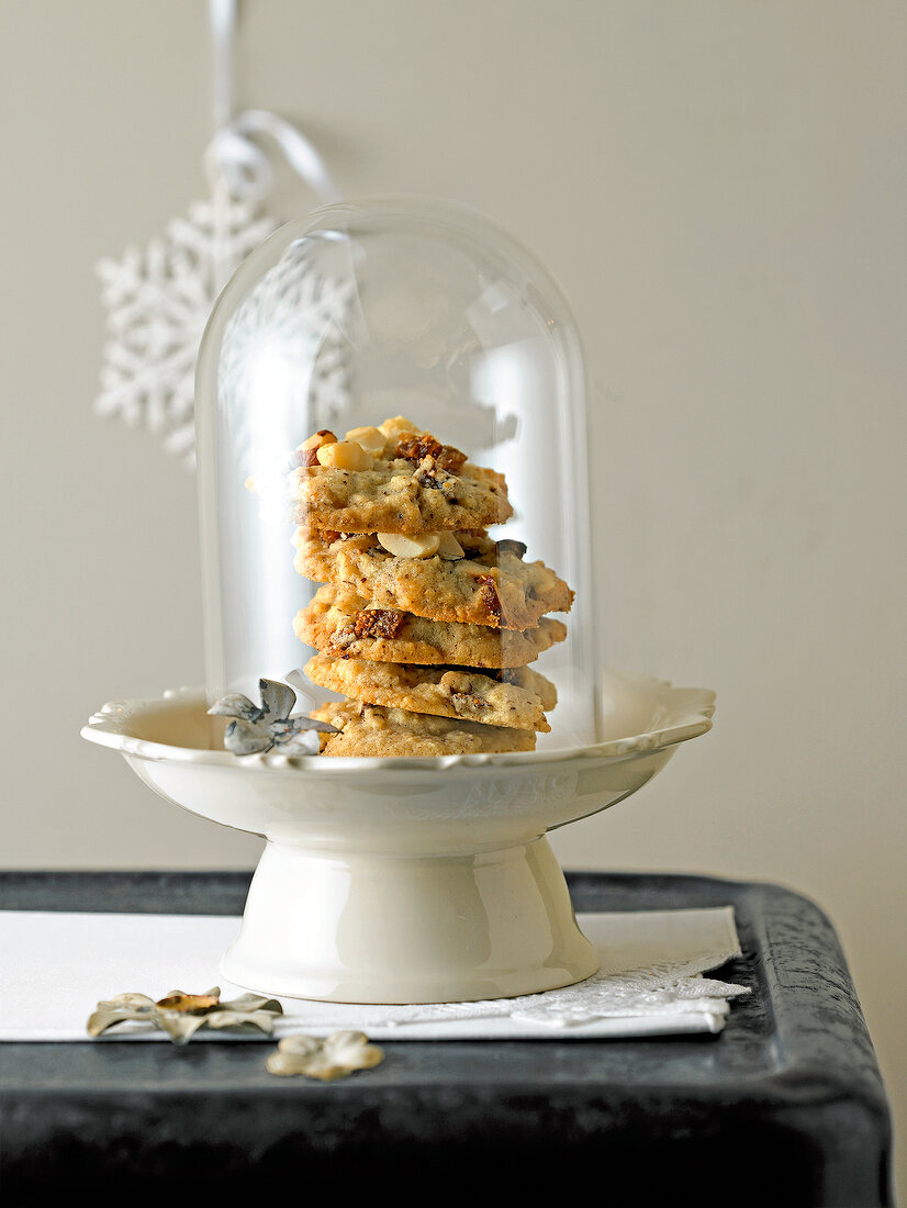 Stack of figs and nut biscuits on fruit stand covered with glass on table