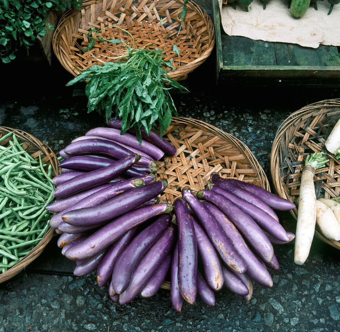 Stack of eggplant and other vegetables in baskets, elevated view