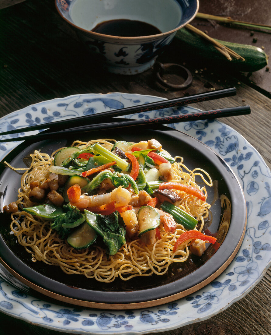 Fried egg noodles with meat and chopsticks on plate