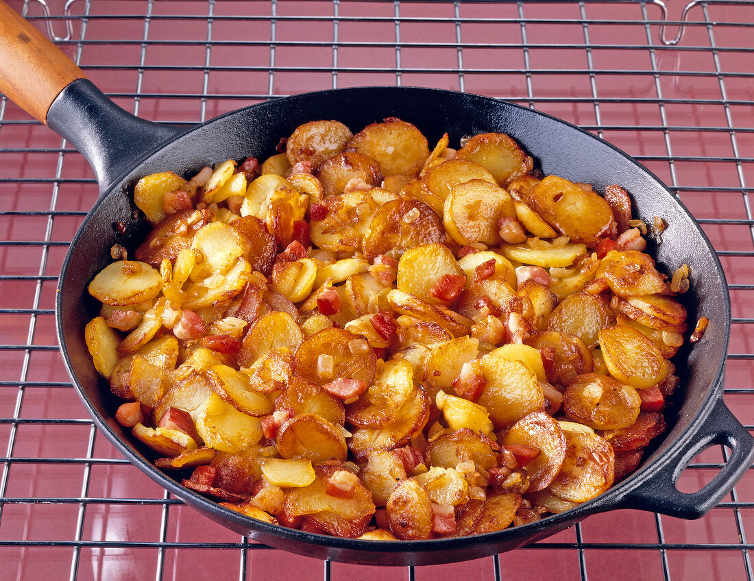 Potatoes with onions and meatballs in skillet pan on grill