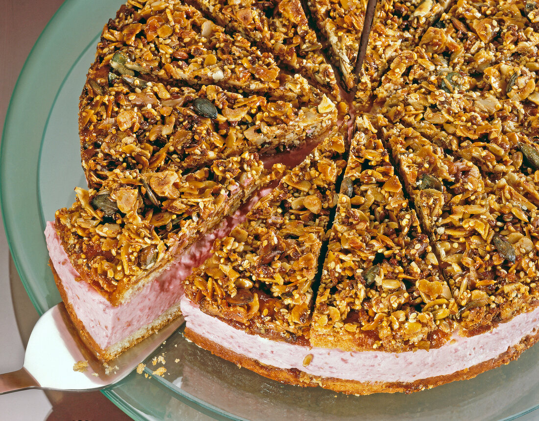 Raspberry nut cake on glass plate with one piece on spatula