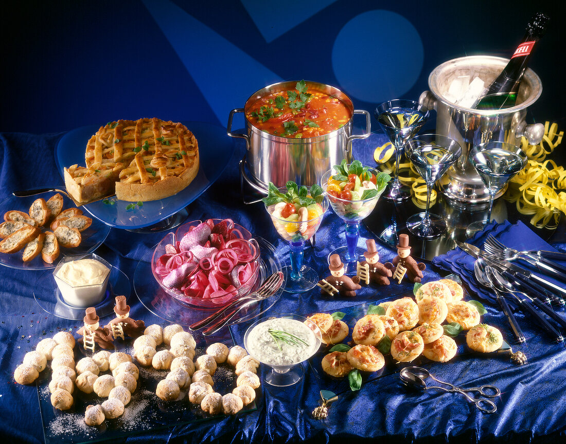 Blauer, gedeckter Tisch mit Suppe, Torte, Sekt, Salat, Brot, Gläser