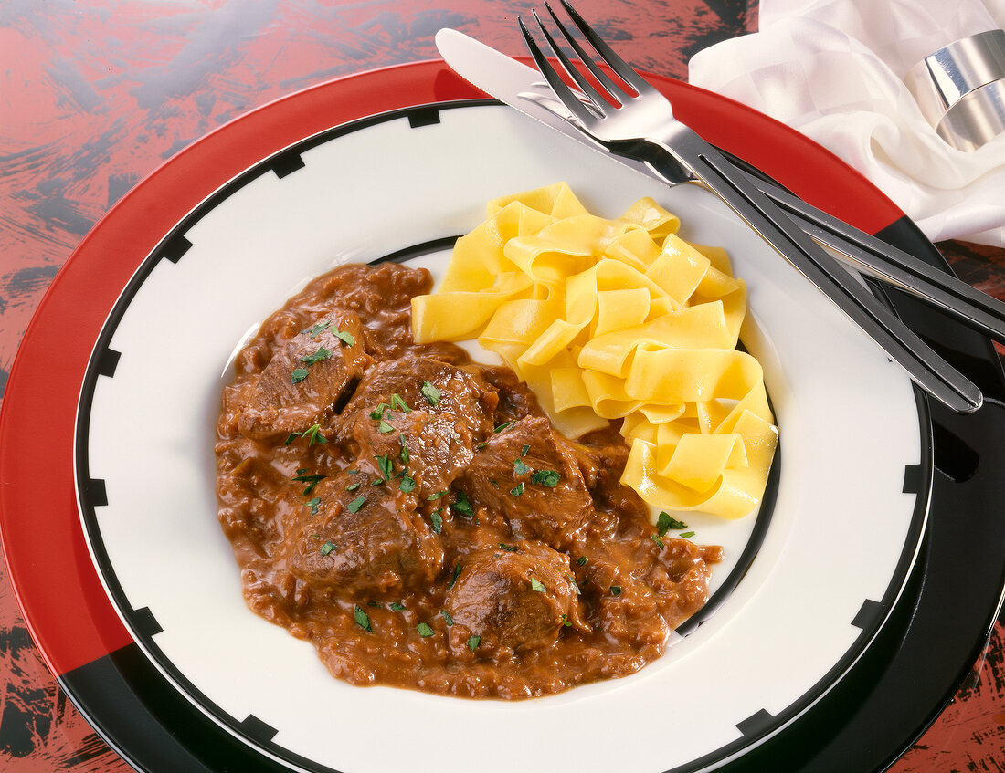 Beef stew with flat noodles on plate