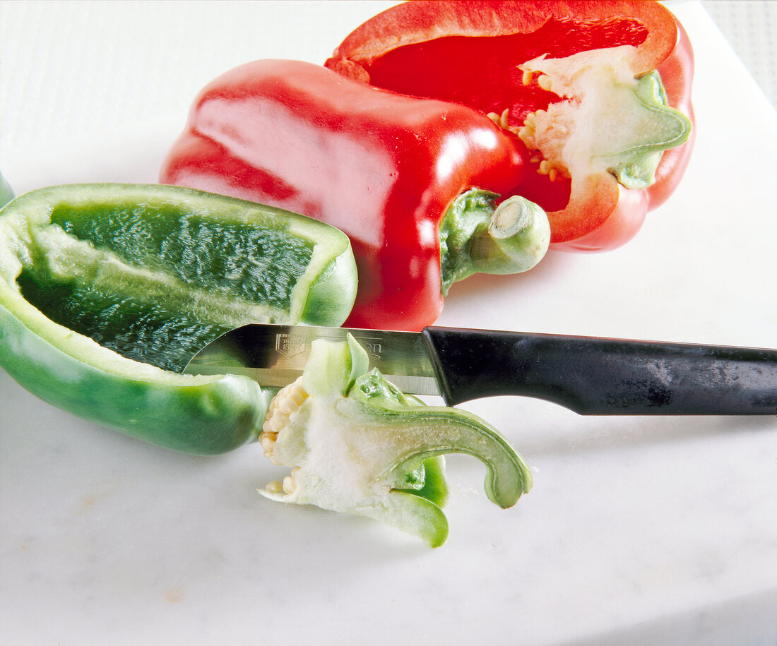 Close-up of knife cutting stalk of halved peppers