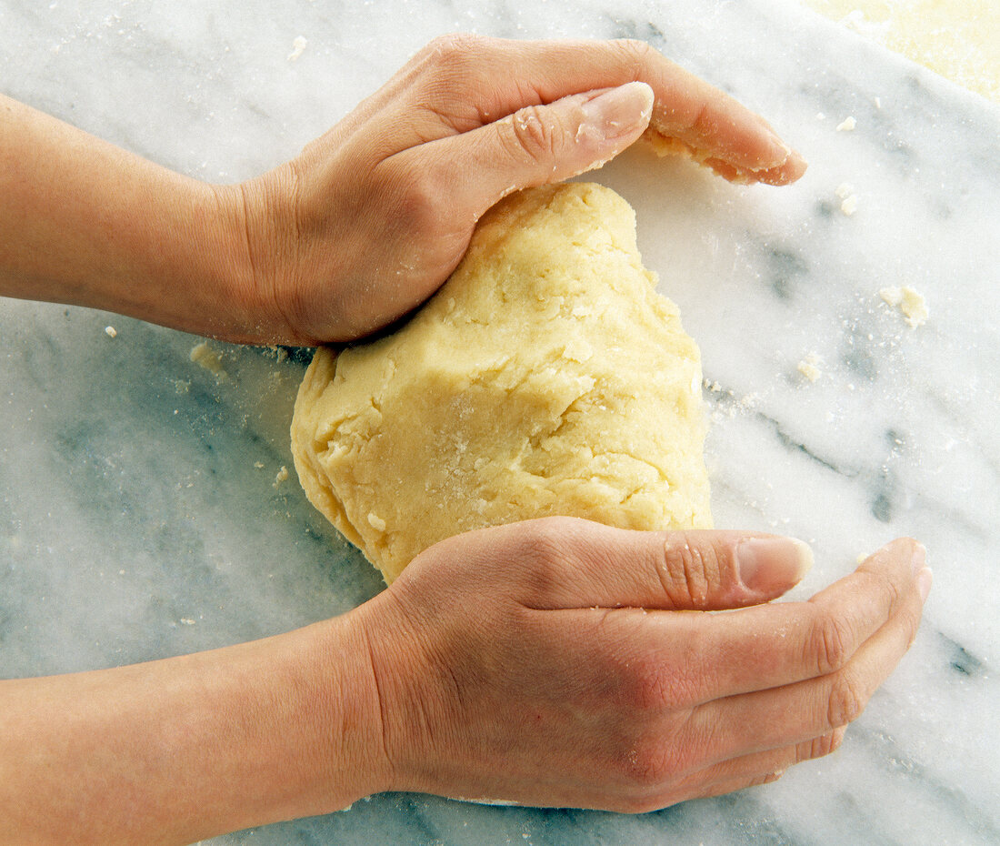 Close-up of woman's hands kneading smooth dough for short crust pastry