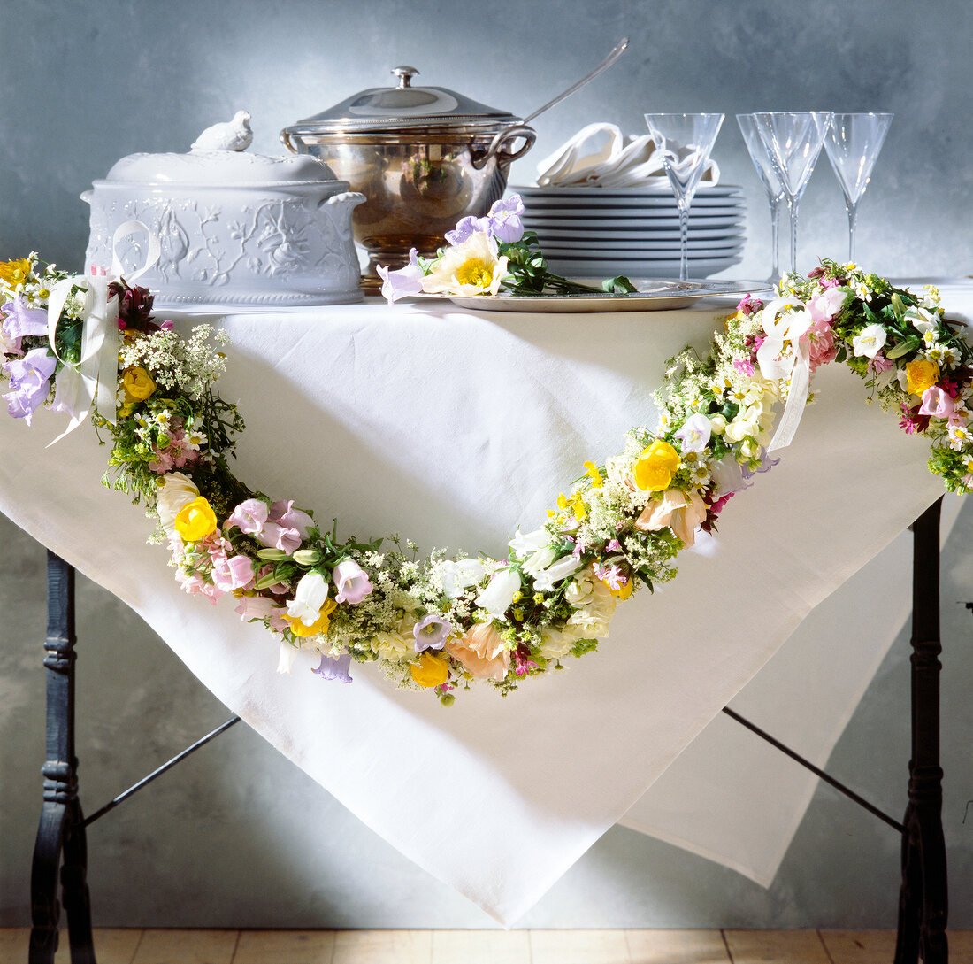 Garland of flowers on dining table with dishes and soup tureen