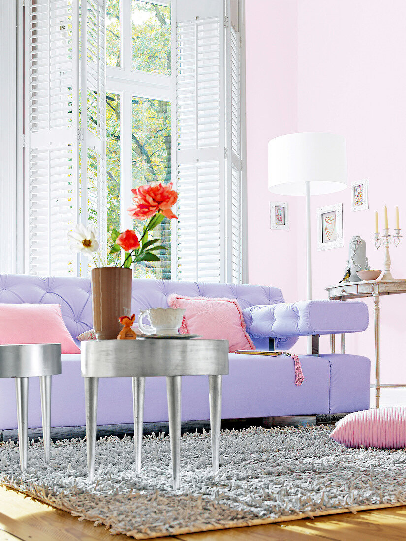 Purple sofa with pink cushions and silver coffee table in living room