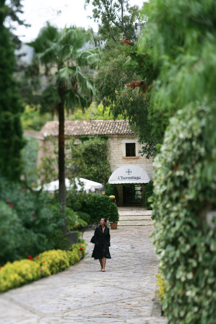 Woman walking on entrance of hotel and Restaurant L`Hermitage in Mallorca, Spain