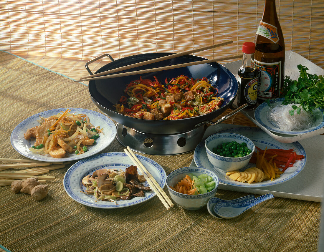 Tofu with vegetables in wok, plates and dishes