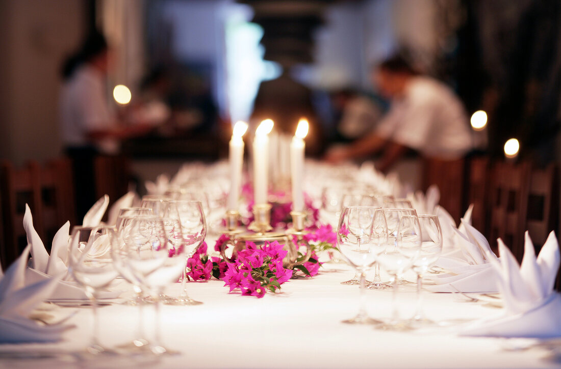 View of large laid white table with flowers, burning candle and glass in Mallorca, Spain