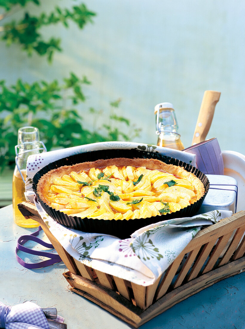 French apple tart in baking tray on basket