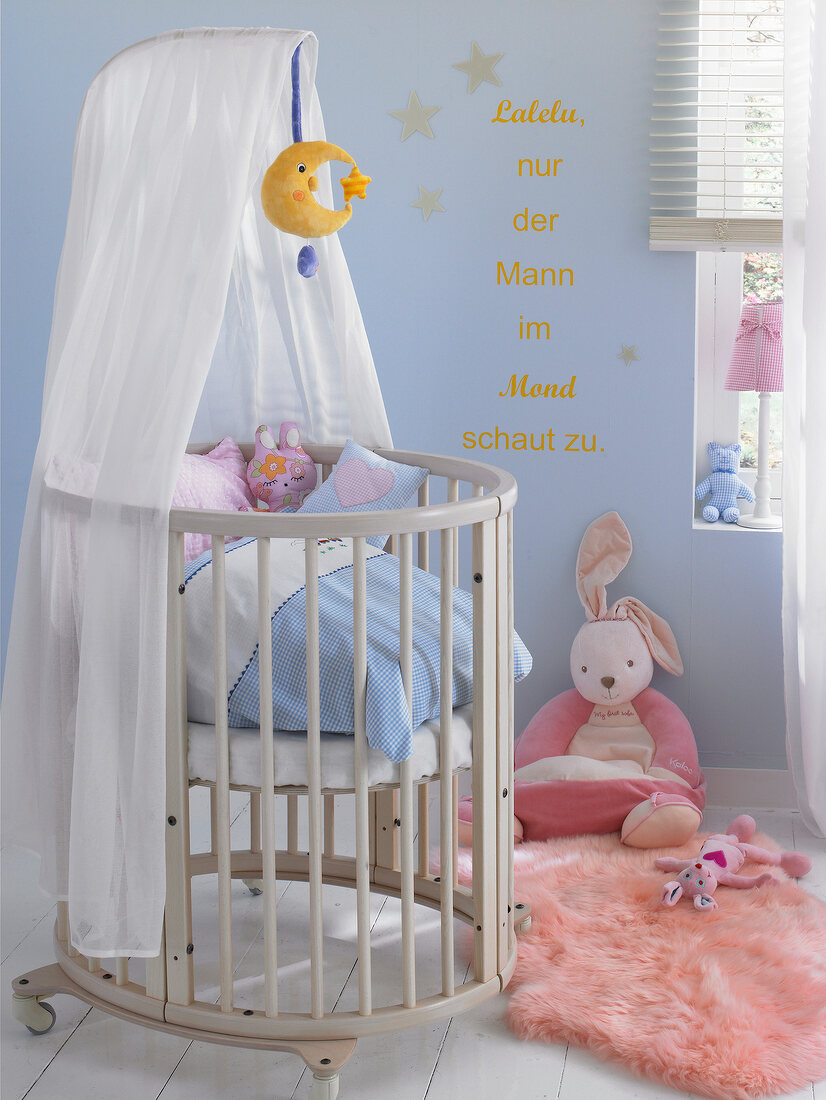Babies room with cot, soft toys and blue wall with text