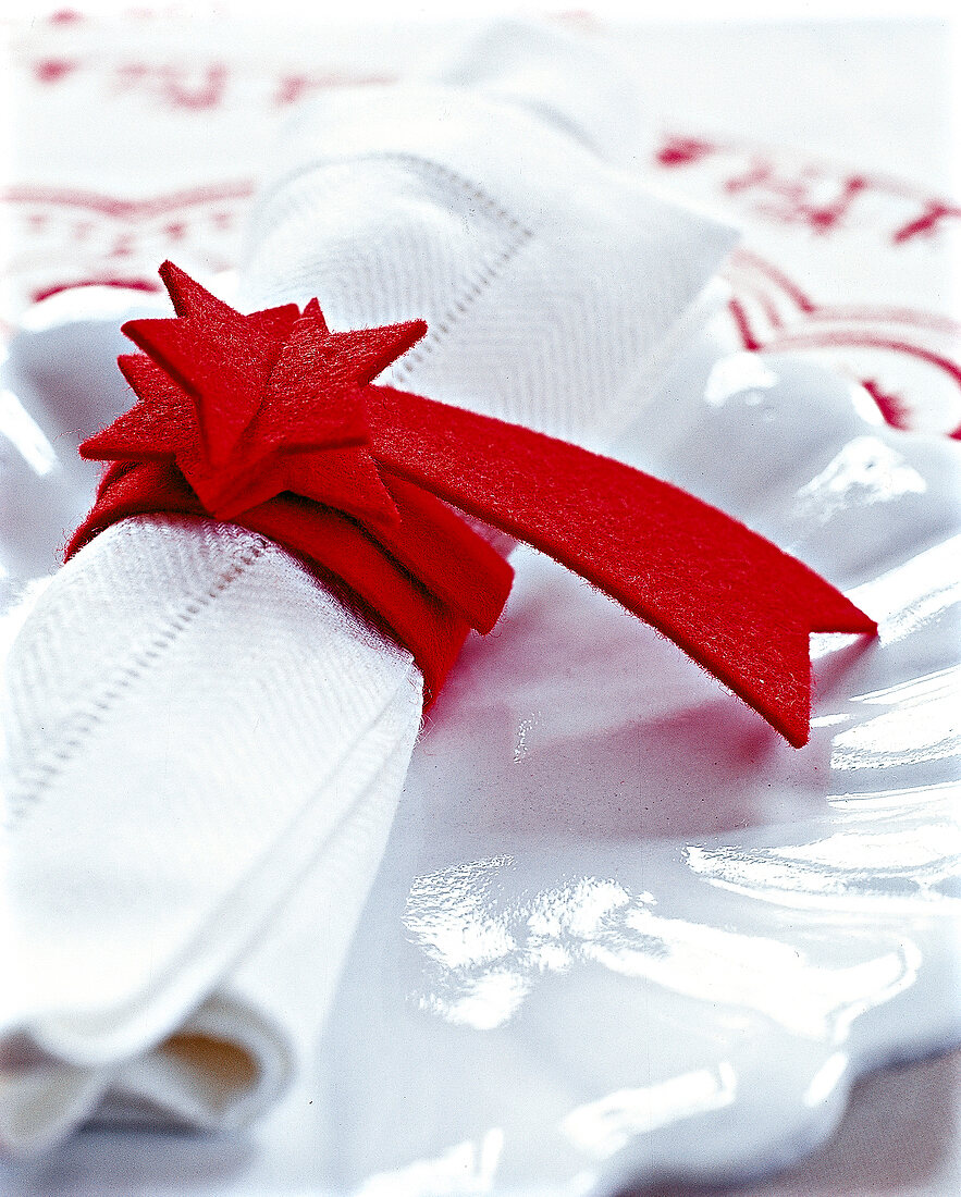 weiße Serviette mit rotem Serviettenring, Sternschnuppe