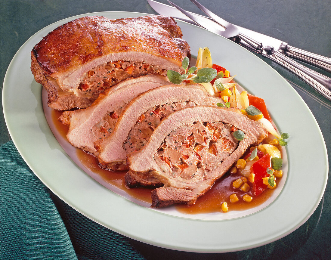 Spicy veal breast stuffed with liver and bell pepper and sweet corn on plate