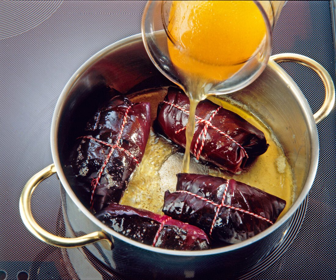 Beef wrapped in red cabbage leaves cooked in pot with broth