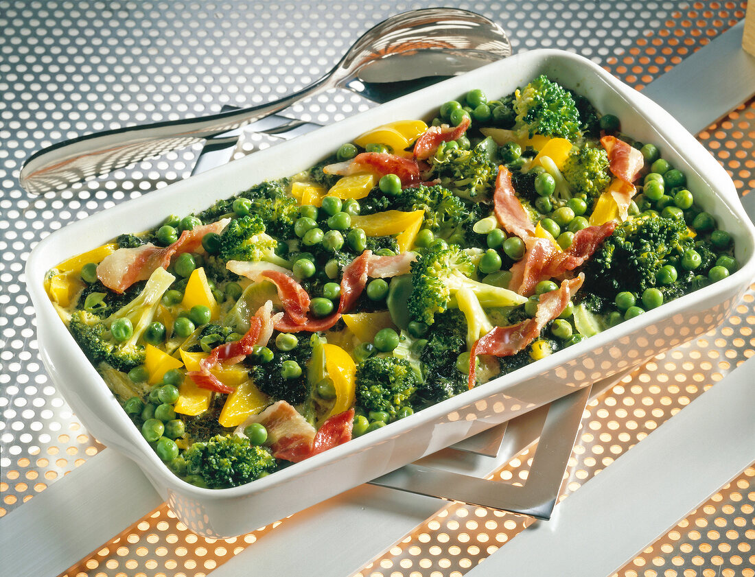 Vegetable casserole with spinach, peas, broccoli and bacon in serving dish