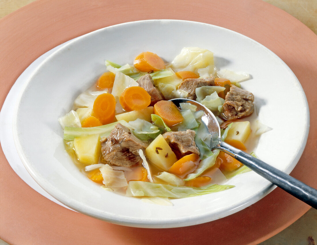 White cabbage stew with carrots and lamb shoulder in a bowl