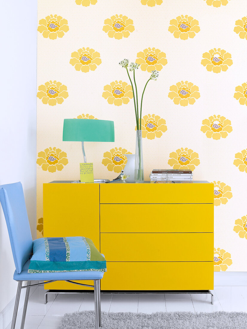Yellow dresser with drawers in front of wallpaper with yellow flowers