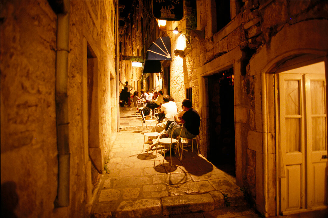 Guests at restaurant in narrow streets of old town on Korcula island, Croatia