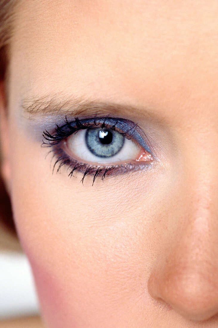 Extreme close-up of gray eyed woman wearing blue eye make-up